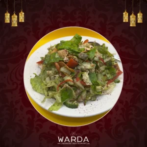 A bowl of Fattoush Salad featuring fresh greens, cherry tomatoes, radishes, and crispy spiced Lebanese bread, dressed in apple vinegar.