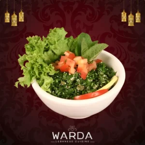 A bowl of Tabbouleh Salad featuring minced parsley, mint, onions, tomatoes, and cracked wheat, tossed in lemon and olive oil dressing.