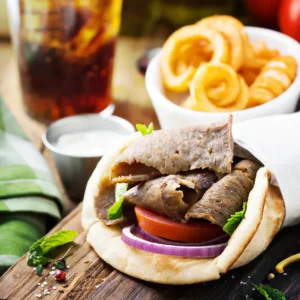 A Lamb Shawarma Wrap With Tender Grilled Lamb Slices, Fresh Vegetables, And Rich Garlic Sauce In Soft Pitta Bread.